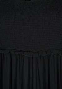 Vestido negro con un corsé fruncido, dobladillo con volantes y tela fluida. Parte superior texturizada con detalle recogido y falda lisa en contraste.