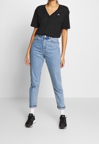 Svart V-ringad T-shirt, kombinerad med högmidjade ljusblå jeans med uppvikta ärmar. Bärs med svarta sneakers och vita ankelsockor.