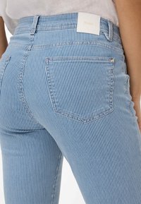 Lichtblauwe gestreepte jeans met een hoge taille, voorzien van witte stiksels, een merkembleem op de achterkant en een traditionele vijf-pocketontwerp.