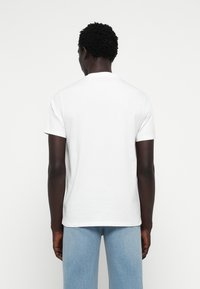 T-shirt bianco in cotone con maniche corte, scollatura rotonda e vestibilità comoda. Indossato con jeans in denim azzurro chiaro.