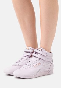 Lila högskor i läder med slät yta, som har dubbla kardborreband, perforerade detaljer och en gummisula.