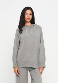 Sweater cinza tricotado com capuz, punhos canelados e bainha inferior. Apresenta um ajuste descontraído e textura suave. Design simples e monocromático.