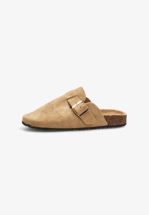 Zuecos de ante beige sin cierre con punta redondeada y hebilla decorativa. Parte superior texturizada y suela tipo corcho para mayor comodidad y soporte.