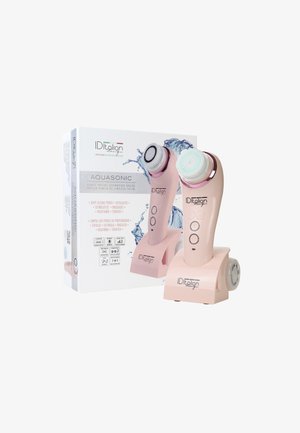 Brosse nettoyante faciale sonore rose avec deux têtes de brosse détachables sur un socle de chargement à côté de sa boîte d'emballage présentant des graphiques d'éclaboussures d'eau.