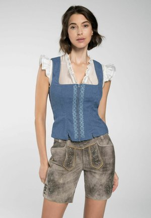 Blaues tailliertes Weste mit Reißverschluss, verziert mit floralen Stickereien, getragen über einer weißen Rüschbluse. Kombiniert mit grauen Shorts, die mit dekorativen Akzenten versehen sind.