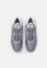 Grå atletik sneakers laget av semsket skinn og mesh, med snøring, polstret krage og et logomerke på tunga.