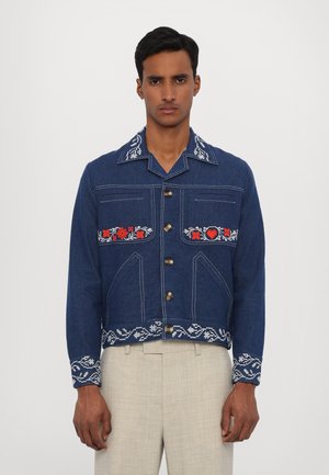 Blue denim jacket with embroidered floral patterns in red and white, featuring a collar, chest pockets, and gold buttons, cropped design.