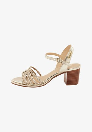 Sandale à talons en cuir doré avec des sangles tressées, une sangle à la cheville avec boucle, et un talon en bois. Fini lisse et design à bout ouvert.