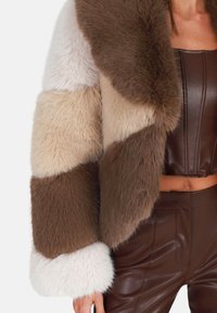 Faux bontjasje met een kleurblokontwerp in crème, beige en bruin. Heeft een pluche textuur en brede, contrasterende witte manchetten.
