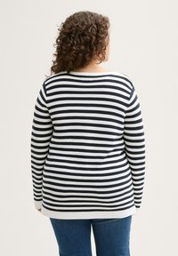 Langarmshirt mit einem navy-weiß gestreiften Muster, gerippter Textur, rundem Ausschnitt und lockerer Passform, kombiniert mit blauen Jeans.