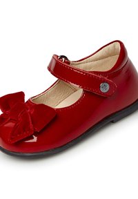 Zapato Mary Jane de charol rojo con punta redondeada, correa ajustable y gran lazo de terciopelo en la parte delantera. Suela de goma negra.