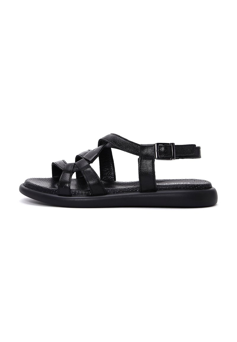 Black leather sandals feature crisscross straps, an adjustable buckle, and a flat rubber sole with a textured insole for grip.