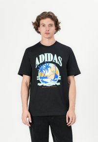 Fekete pamut póló színes pálmafák és egy vitorlás grafikájával. Az "ADIDAS" felirat jellemzi és laza fazonú.