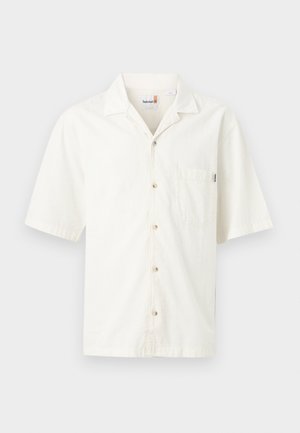 Camisa blanca de manga corta con botones, bolsillo delantero y cuello, con el logotipo de Timberland en la etiqueta interior del cuello.