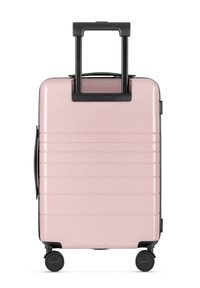 Valigia rigida di colore rosa con dettagli neri, strisce texturizzate, manico estensibile e quattro ruote per una facile manovrabilità.