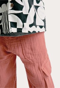 Zwart-wit gestreept overhemd met korte mouwen, gecombineerd met roze textuur broek met zakken en een ontspannen pasvorm.