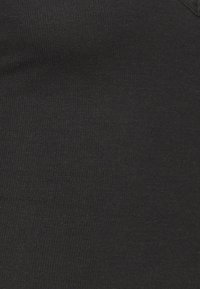 Textura de tecido preto com relevo e acabamento suave, apresentando finas linhas verticais. O material parece elástico e ajustado ao corpo.