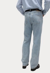 Jeans de mezclilla en azul claro con un diseño de pierna recta, que cuentan con dos bolsillos traseros y un parche de cuero marrón en la cinturilla.