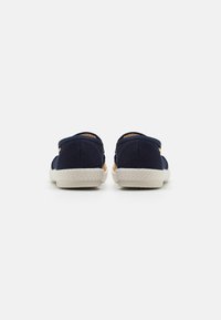 Chaussures en toile marine à design basse, avec des panneaux latéraux élastiques et des accents en corde naturelle sur la semelle pour plus de texture et de détail.