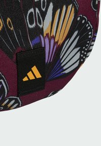 Colorful butterfly-patterned bag featuring a black rectangular tag with a yellow Adidas logo. Material appears durable with a textured surface.