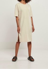 Beige, puuvillamekko, lyhyet hihat, suora leikkaus, sivuhalkiot ja pyöreä kaula-aukko. Yhdistetty mustiin sandaaleihin. Yksinkertainen malli, rento ilme.