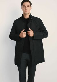 Czarny syntetyczny płaszcz z wysokim kołnierzem, zapięciem na zatrzaski z przodu i długimi rękawami. Posiada prosty krój i gładką teksturę.