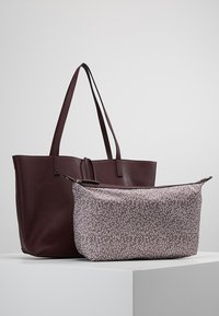 Grande borsa a tracolla in pelle borgogna con manici lunghi, abbinata a un piccolo astuccio con zip caratterizzato da un motivo floreale bianco su uno sfondo rosa chiaro.