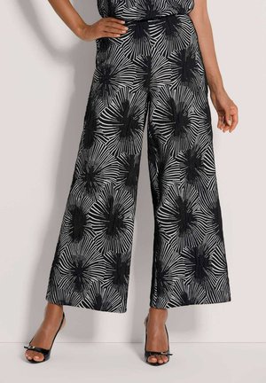 Wide-leg pants feature a black and white floral pattern with bold lines. The fabric appears lightweight, with a smooth texture and relaxed fit.
