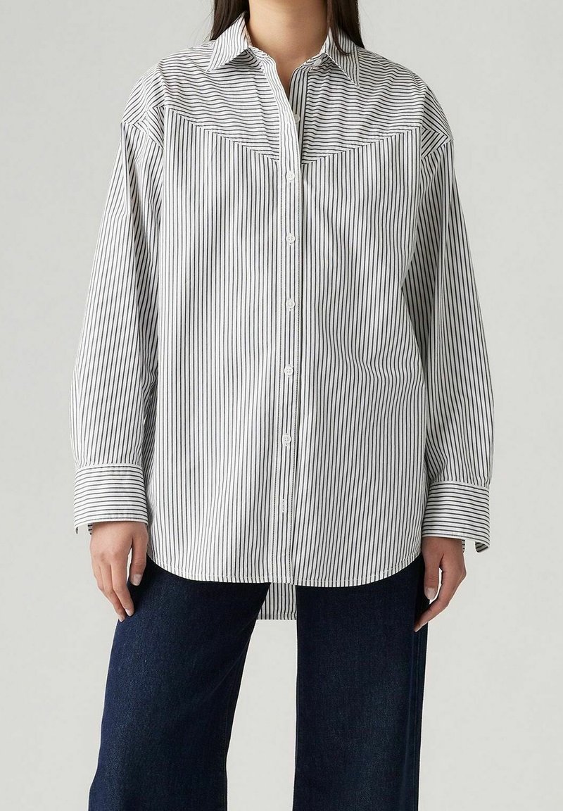 Chemise à rayures boutonnée en noir et blanc, dotée d'un col classique, d'une poche poitrine et de larges poignets. Tissu doux avec une coupe décontractée.