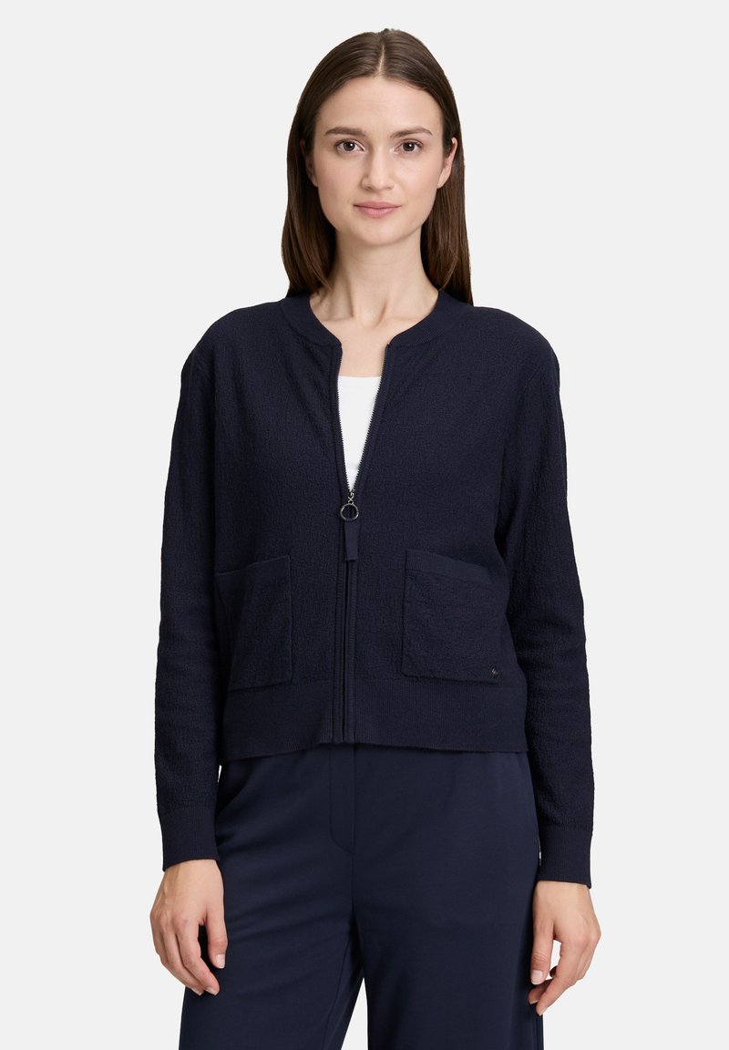 Navy Zip-Up-Strickjacke mit strukturierter Oberfläche, rundem Ausschnitt und zwei Fronttaschen. Mit verkürzter Länge und langen Ärmeln gestaltet.