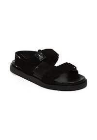 Svart sandal med dubbla remmar, spänne och en dämpad fotbädd. Sulan är texturerad för bra grepp och har en platt design.