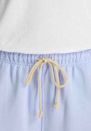 Light blue elastic waist pants with a beige braided drawstring tied in a bow, paired with a white top.
