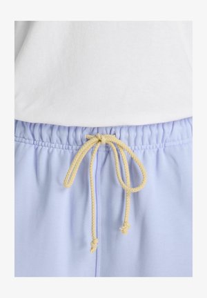 Light blue elastic waist pants with a beige braided drawstring tied in a bow, paired with a white top.