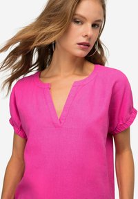 Top corto fucsia a maniche corte con scollatura a V e maniche arricciate, realizzato in un materiale leggero con una texture liscia.