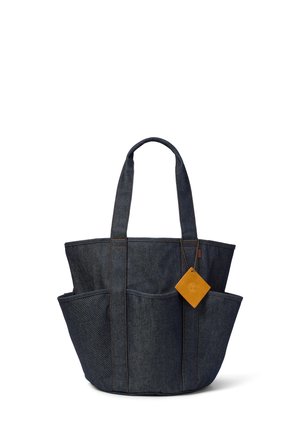 Borsa tote in denim scuro con due manici, tre tasche esterne e una piccola targhetta in pelle marrone attaccata a un manico.