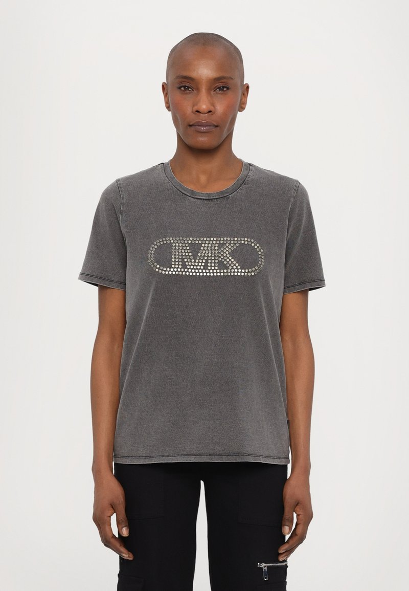 Camiseta de algodón gris con cuello redondo, mangas cortas y un diseño de logo con clavos plateados en el frente. Textura ligeramente desgastada.