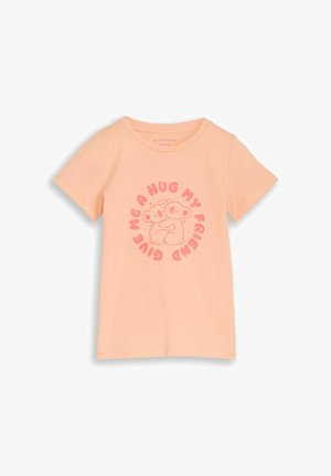 Camiseta de manga corta color melocotón claro con ilustración de dos koalas abrazándose y texto circular "Dame un abrazo, amigo" en rosa.