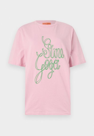 T-shirt rosa de manga curta com texto em verde em caligrafia que diz "Stine Goya." Feito de um tecido macio, com um decote redondo clássico.