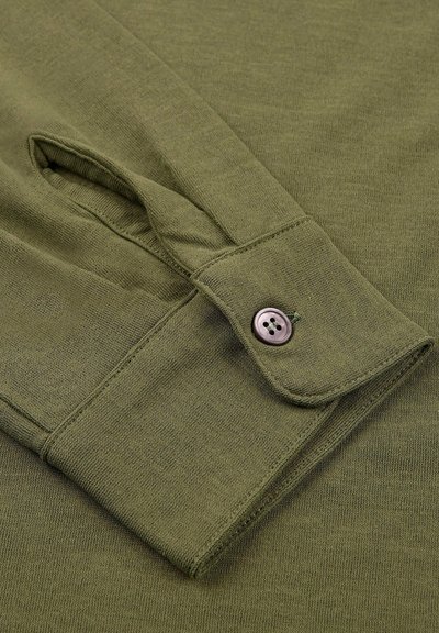 Poignet de chemise à manches longues vert olive avec un bouton de fermeture ; tissu doux et texturé ; dispose d'une ouverture avec patte et d'un bouton visible.
