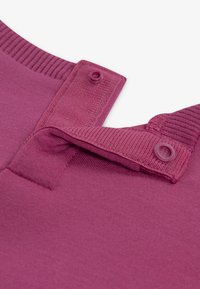 Tissu en mélange de coton bourgogne, présentant un col côtelé, deux boutons de fermeture et une texture lisse avec un design de couture plate.
