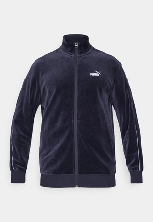 Chaqueta azul marino con cremallera hecha de un material de terciopelo suave. Presenta un cuello alto, el logo blanco de Puma y franjas blancas en las mangas.