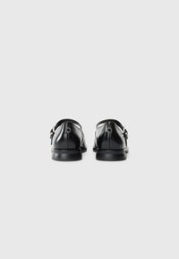 Pair of black leather dress shoes with silver buckles, viewed from the back on a plain white background.