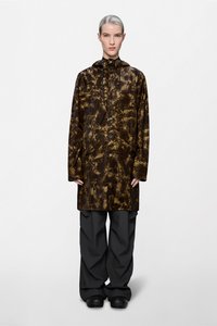 Καφέ αδιάβροχο με σχέδιο tie-dye, κουκούλα, κουμπιά τύπου snap και πλαϊνές τσέπες· συνδυασμένο με φαρδιά γκρι αδιάβροχα παντελόνια και μαύρα παπούτσια.