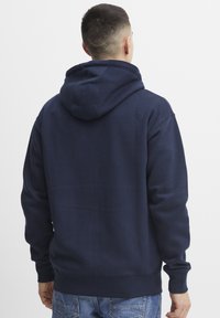 Navy blue hooded sweatshirt with a relaxed fit, thick fabric, and ribbed cuffs. Features a large hood and kangaroo pocket at the front.