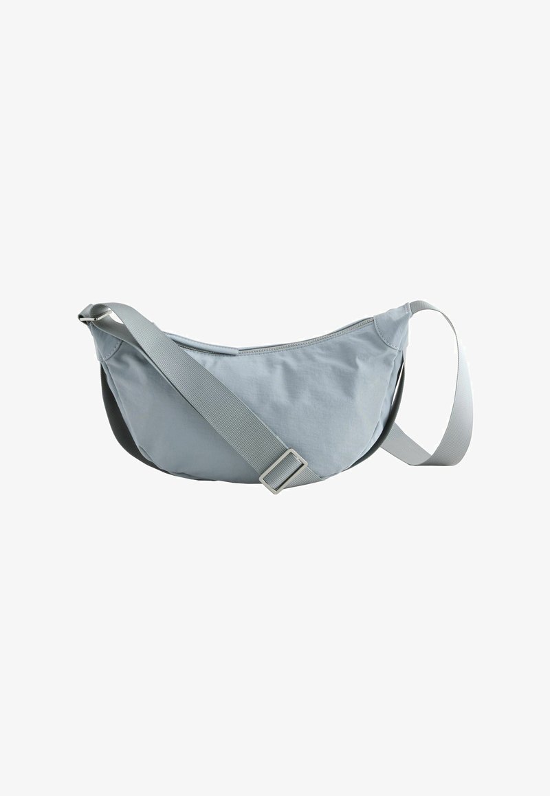Sac bandoulière gris clair en forme de croissant avec bandoulière ajustable et fermeture éclair supérieure, isolé sur fond blanc.