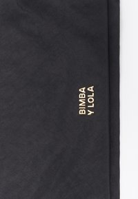 Tela negra texturizada con el logo dorado en relieve "BIMBA Y LOLA". El diseño presenta líneas limpias y un acabado mate suave.