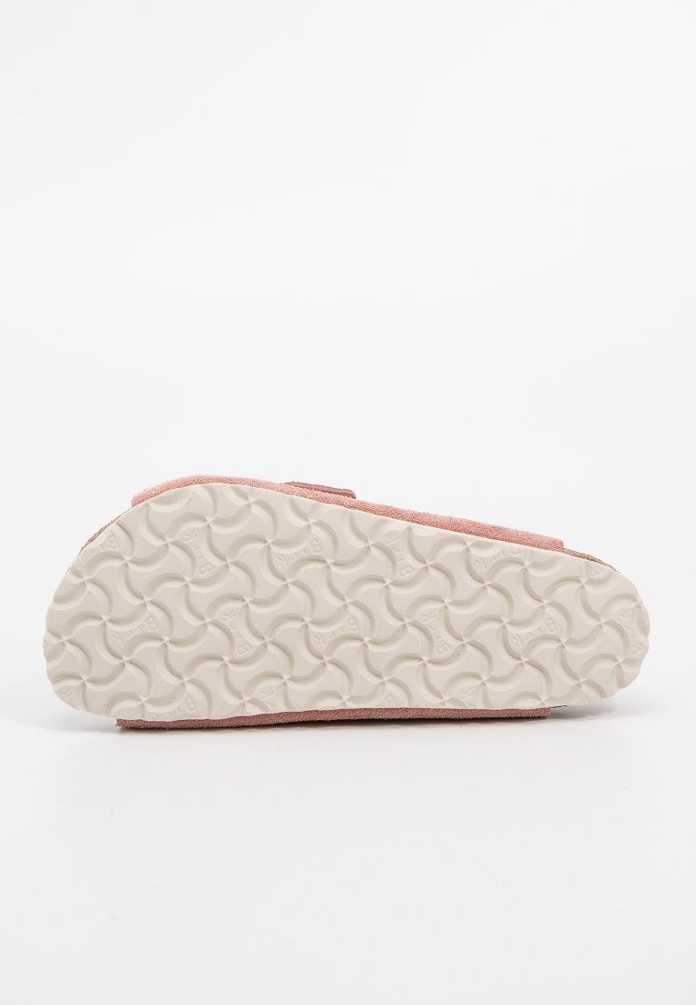 Beiger Gummisohle mit genoppter Profilierung, obere Kanten aus pinkem Wildleder, sichtbar entlang der Seiten, auf weißem Hintergrund fotografiert.