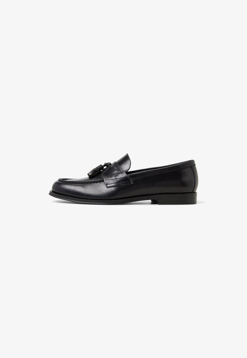 Black leather loafer with a rounded toe, decorative tassels, subtle stitching, and a low block heel. Smooth texture with a polished finish.