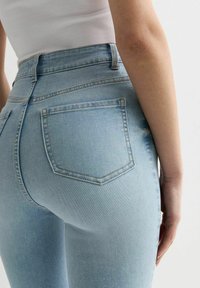 Lichtblauwe high-waisted jeans met een aansluitende silhouette, voorzien van twee achterzakken, subtiele vervaging en contraststiksels.