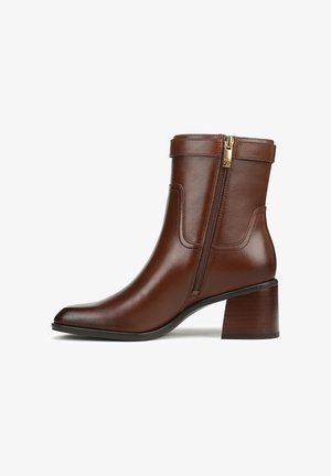 Bruine leren enkelboot met een spitse neus, zijrits en een gestapelde houten hak. Gladde textuur met minimaal stikseldetails.
